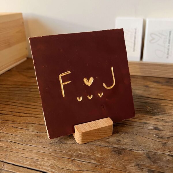 Tegeltje met een letter een hartje een letter en drie kleine hartjes