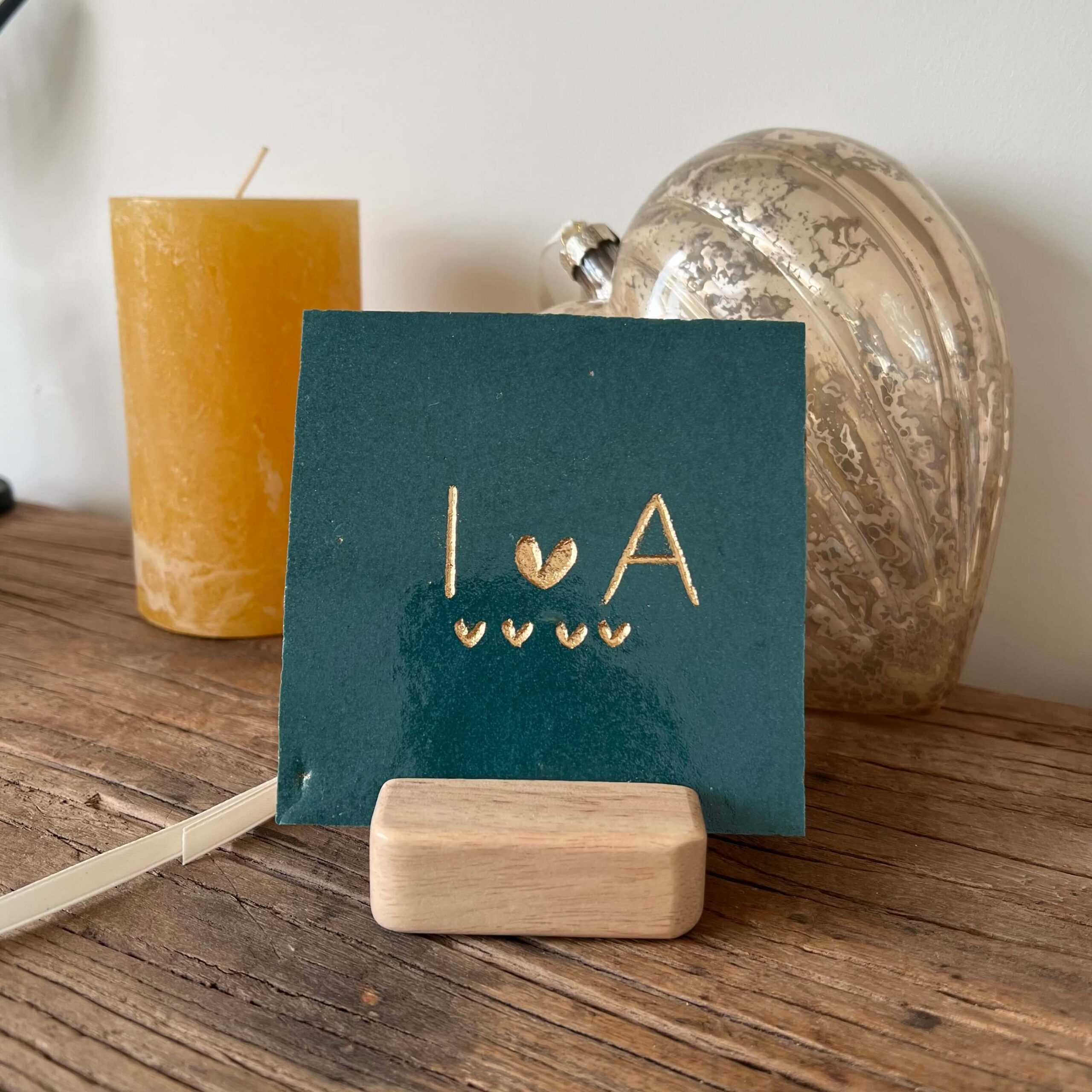 Tegeltje met een letter een hartje een letter en vier kleine hartjes